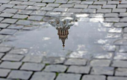 Vista de la cúpula de la basílica de San Pedro reflejada en un charco tras el anuncio de renuncia hecho por el papa Benedicto XVI.