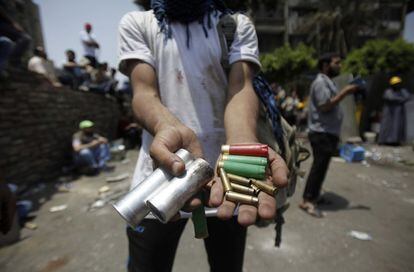 Un miembro de los Hermanos Musulmanes muestra casquillos de balas y botes de gases lacrimógenos en el lugar donde esta madruga el ejército egipcio ha disparado a los seguidores del expresidente egipcio Mohamed Morsi, 8 de julio de 2013.
