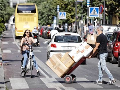 Una mujer circula con una bicicleta de Bicimad por el carril bici de la calle Mayor.
