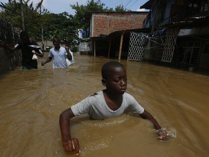 Niños caminan por barrios inundados por el desbordamiento del río Cauca en Cali (Colombia), el 12 de noviembre de 2022.