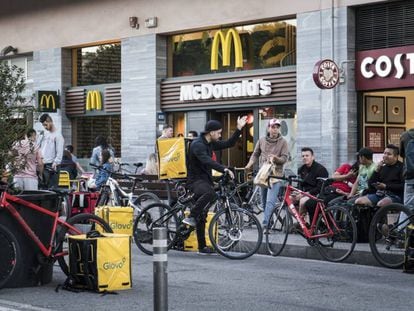 Diversos repartidors esperen davant d'un establiment de menjar ràpid a Barcelona.