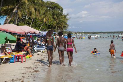 Tres jóvenes pasean por la playa de Boca Chica.