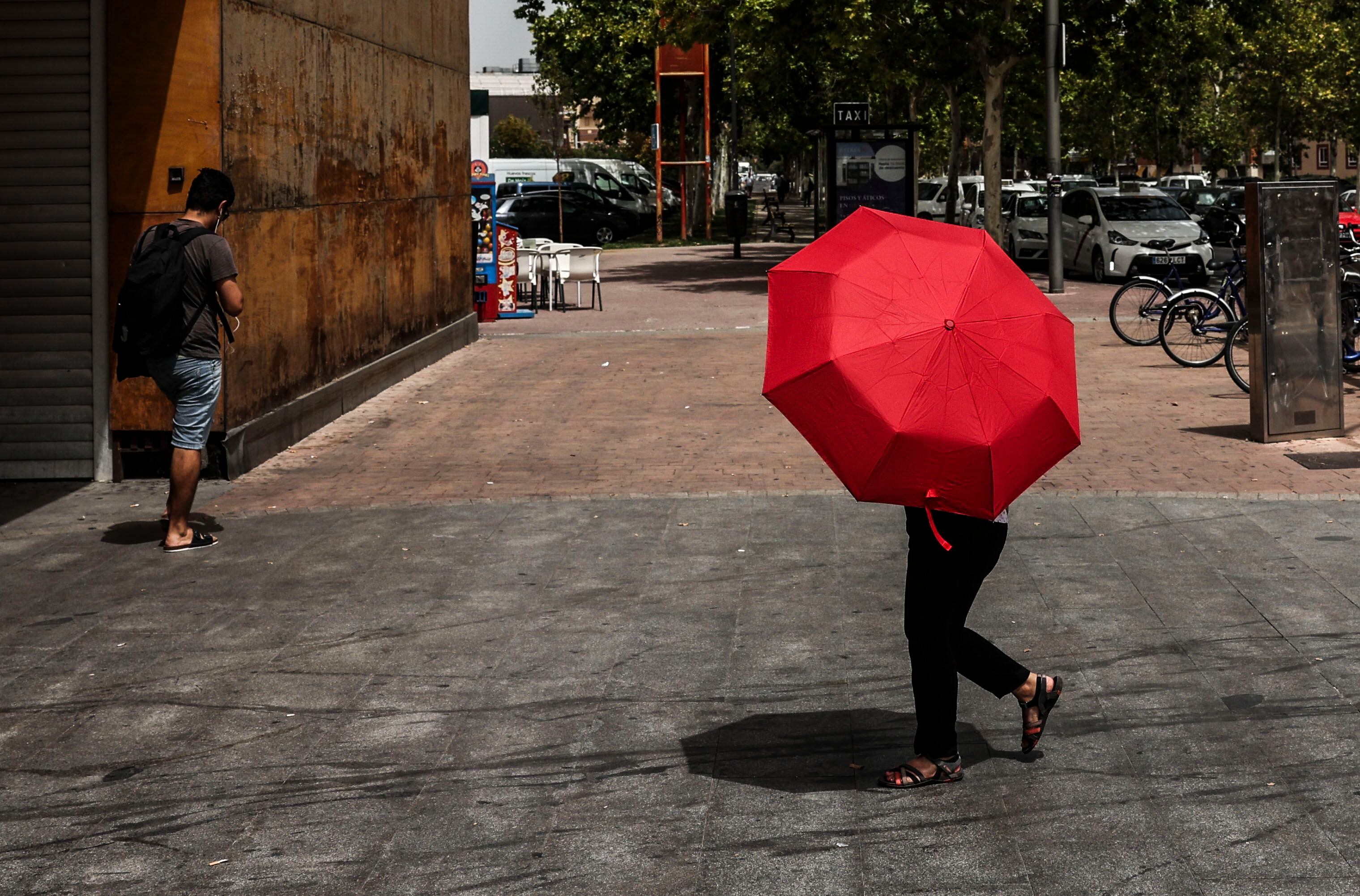 Una persona se cobre del sol con un paraguas en una calle de Getafe.
