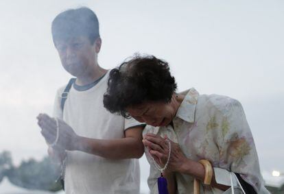 Dos personas rezan por las víctimas de la bomba atómica durante la ceremonia realizada en el parque Memorial de la Paz de Hiroshima (Japón).