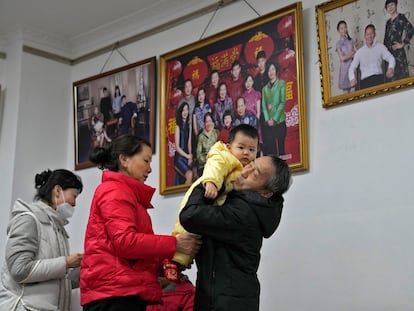 Un abuelo sujeta a su nieto después de hacerse unas fotos con los miembros de su familia, en un estudio de Pekín (China), este martes.