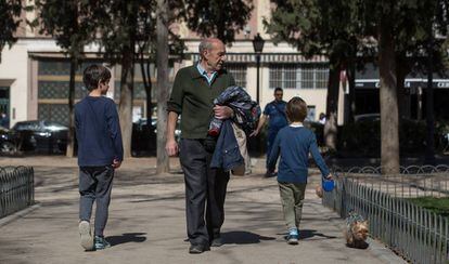 Dos niños y un hombre mayor pasean por un parque de Madrid.