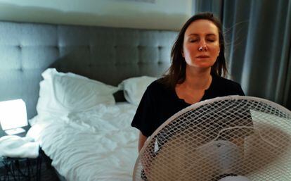 Una mujer intenta refrescarse frente a un ventilador.