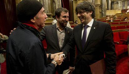 Llach (i) y Puigdemont se dan la mano en presencia de Comín.