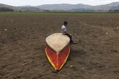 <b>Guatemala.</b> Un niño permanece sentado sobre un bote en el terreno seco sobre el que estuvo el lago Atescatempa.