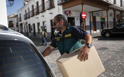 Un guardia civil con una caja de evidencias tras registrar el Ayuntamiento de Valdemoro.
