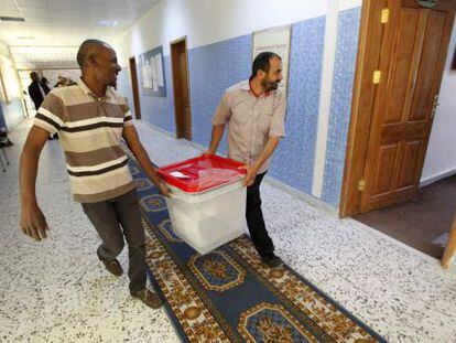 Dos funcionarios libios trasladan una urna en Tr&iacute;poli.