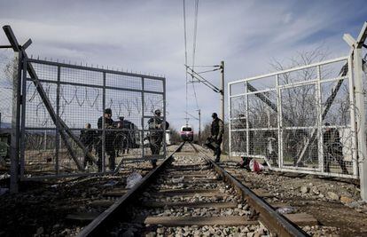 Policías macedonios abren la puerta que separa la frontera para que pase un tren, junto al campamento de refugiados de Idomeni, el 8 de marzo del 2016.
