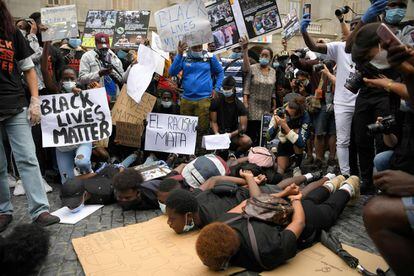 Los concentrados en Barcelona, con una rodilla en el suelo y bajo la lluvia, exhibieron fotografías de la víctima y pancartas con lemas como "No al racismo", "Black lives matter" y otras consignas contra el presidente Trump.