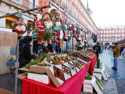 Varias personas visitan el Mercado de Navidad instalado en la plaza Mayor de Madrid.