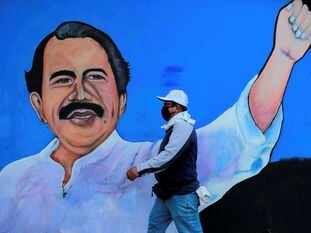 Un hombre camina frente a un mural de Daniel Ortega en Managua.