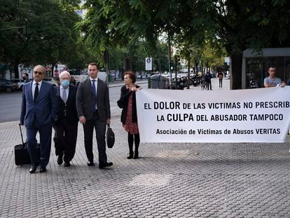 El psiquiatra Javier Criado (centro) llega a los juzgados de Sevilla este miércoles, recibido por una pancarta de la asociación de sus supuestas víctimas.