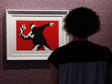 Una mujer observa una obra de Banksy, El lanzador de flores, en una exposición en Roma.