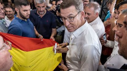 El presidente del PP, Alberto Núñez Feijóo, firma una bandera de España a su llegada al mitin de Murcia el día 12.