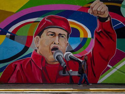 Un hombre camina junto a un mural sobre el fallecido presidente venezolano Hugo Chávez, el 8 de noviembre de 2021 en Caracas, Venezuela,