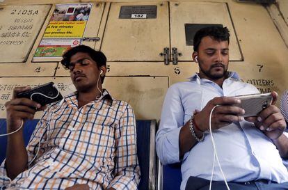 Dos viajeros usan sus teléfonos móviles en el metro de Bombay, India.