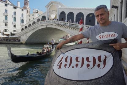 Matteo Secchi, presidente de Venessia.com, sujeta frente al puente de Rialto una pancarta que indica el número de residentes que quedan en Venecia.