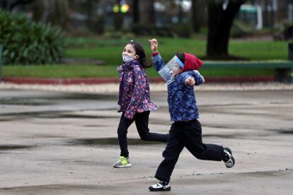 Dos niños con mascarilla juegan en un parque bonaerense cuando el Gobierno argentino comenzó a flexibilizar el confinamiento en el país, en julio de 2020.