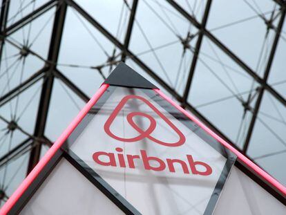 El logo de Airbnb al lado de la pirámide del museo Louvre de París, Francia. 