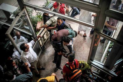 Dos manifestantes evac&uacute;an a un herido en los enfrentamientos de hoy en El Cairo. 
