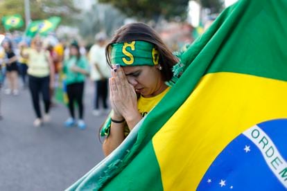 Una partidaria de Bolsonaro reza mientras sigue el conteo de votos en una pantalla gigante en el área de Barra de Tijuca, en Río de Janeiro, este domingo.