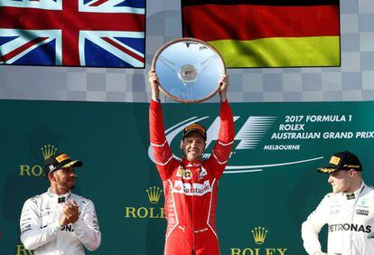 El piloto Sebastian Vettel (c) de la escudería Ferrari celebra su victoria en el pódium junto con Lewis Hamilton (izquierda) y Valtteri Bottas, en segunda y tercera posición.