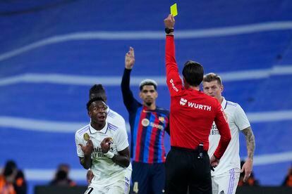 El árbitro José Luis Munuera Montero muestra una tarjeta amarilla al jugador del Real Madrid Vinicius Junior