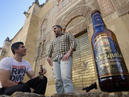 Dos jóvenes beben cerveza Mezquita junto al monumento cordobés.