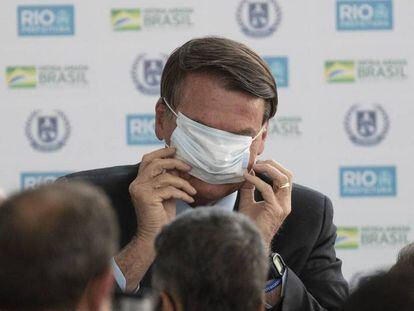 El presidente de Brasil, Jair Bolsonaro, intenta colocarse la mascarilla durante la inauguración de la nueva escuela cívico-militar General Abreu en Río de Janeiro.