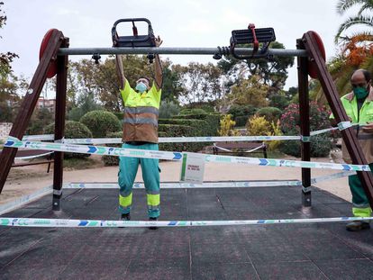 Varios operarios precintan unos columpios en un parque de Valencia el 18 de septiembre.