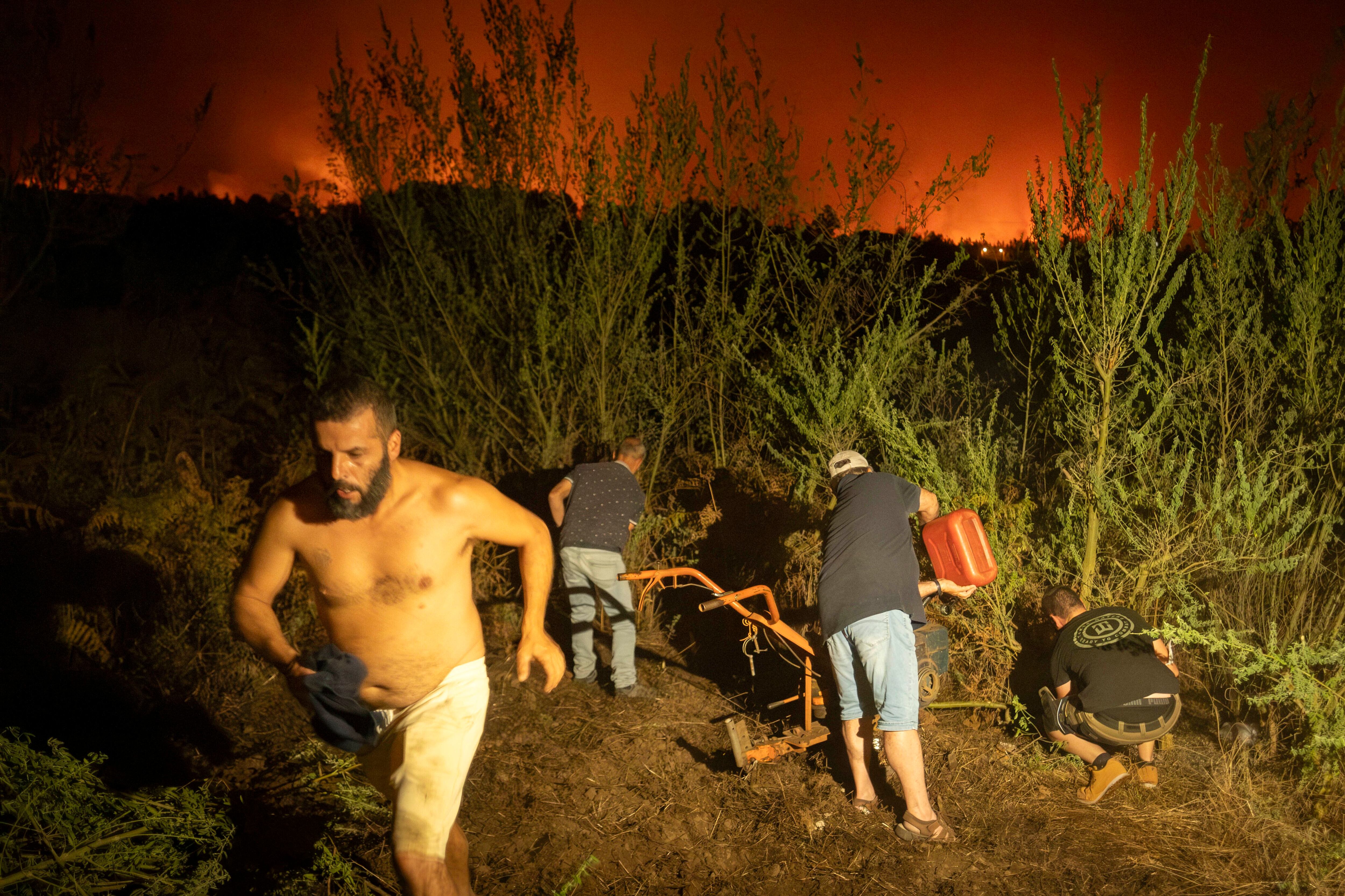 Los residentes locales intentan limpiar el bosque para evitar que el incendio avance a La Orotava, el sábado.