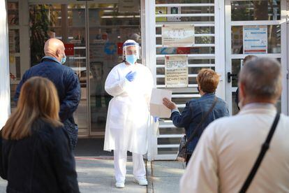 Una sanitaria sale a atender a las personas que hacen cola en un centro de salud en Vicálvaro (Madrid), este lunes.