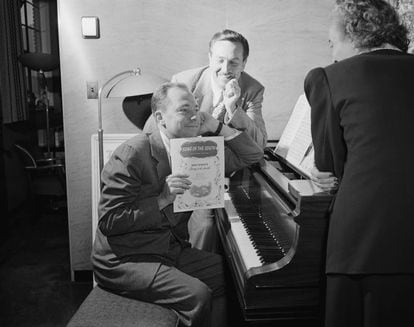 Walt Disney, en el centro, con el músico Johnny Mercer, en el piano con la partitura de 'Canción del sur', en 1946.