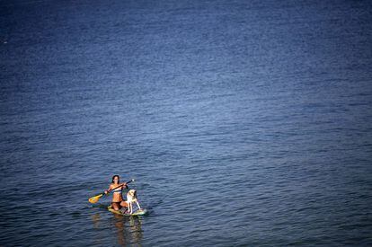 Una mujer rema junto a su perro en la playa de Arpoador, en Río de Janeiro (Brasil), el 31 de enero 2014.