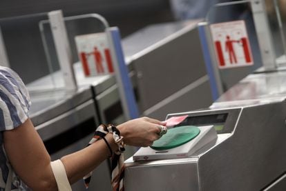Una mujer pasa su tarjeta de transporte público por el torno del Metro Plaza de España, en Madrid, el 6 de julio de 2020.
