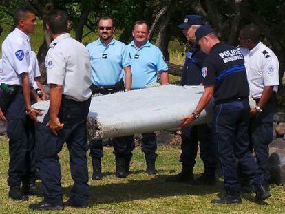 Polic&iacute;as y gendarmes transportan el aler&oacute;n hallado en Reuni&oacute;n.