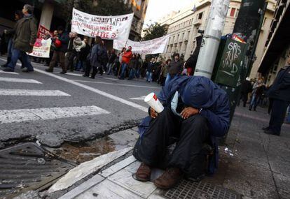 Un mendigo pide lismona al paso de una manifestaci&oacute;n contra los recortes en Atenas.