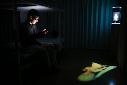 Akihiko Kondo uses his phone with 'Hatsune Miku' in the background before going to bed at his house on September 11, 2018 in Tokyo, Japan