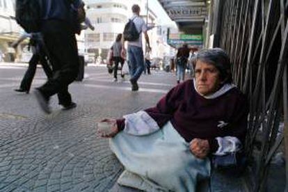 Una anciana indigente pide limosna a los transeúntes del centro de Montevideo. EFE/Archivo