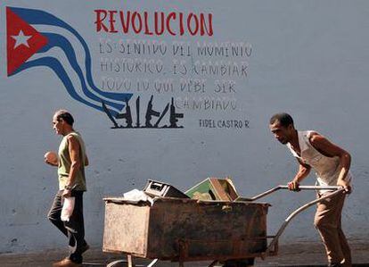 Un hombre empuja una carretilla junto a un cartel alusivo a la revolución en una calle de La Habana en una imagen de archivo