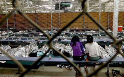 Dos niñas siguen un partido del Mundial desde uno de los recintos donde se está procesando a cientos de menores inmigrantes de Centroamérica.