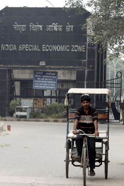 Un hombre pedalea frente a la zona especial de Noida, junto a Nueva Delhi (India).