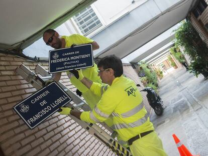 Dos operarios municipales cambian las placas de una de las calles.