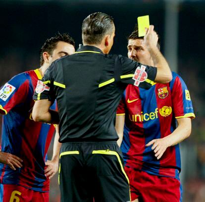 Múñiz Fernández le enseña una tarjeta amarilla a Villa delante de Xavi.