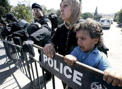 Una palestina y su hijo esperan en la valla policial tras haber sido desalojados de su casa.
