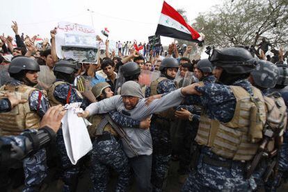 La policía impide a un manifestante entrar en la sede del Gobierno en Basora (sur de Irak).